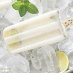 Close up of a creamy Coconut Mojito Ice Pop showing slices of lime and fresh mint in the creamy coconut cocktail popsicle.