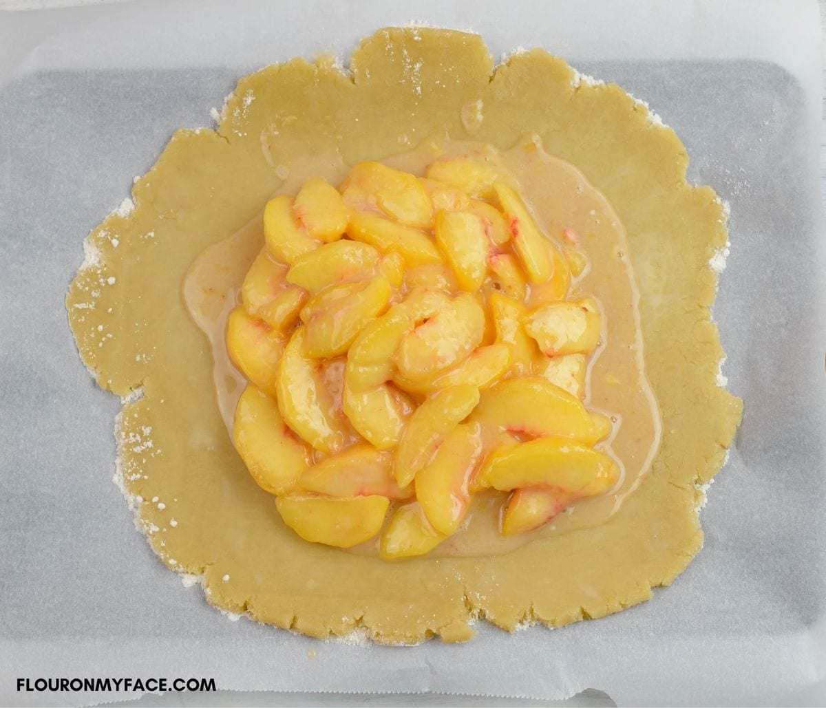 Flat pie crust with a mound of peach pie filling in the center.