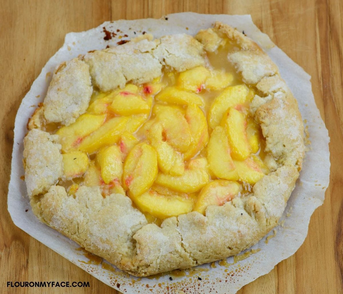 A freshly baked peach galette on a wooden cutting board.