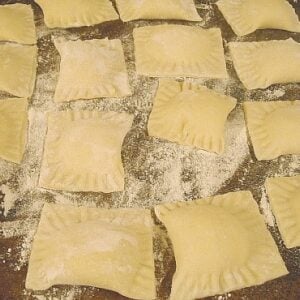 homemade ravioli covered with flour on a cookie sheet