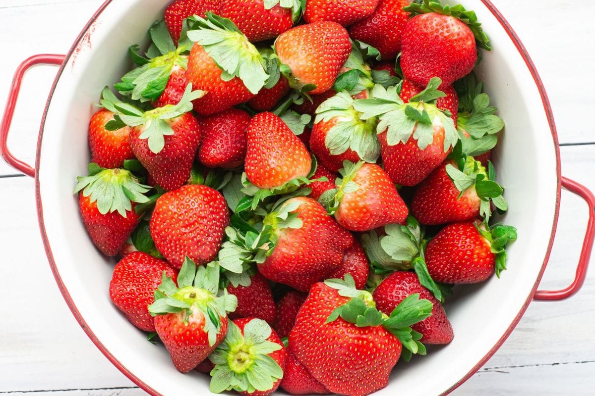 Fresh whole strawberries in a colander after rinsing.