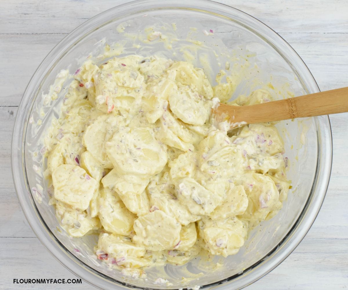 Mixing potato salad ingredients with a wooden spoon.