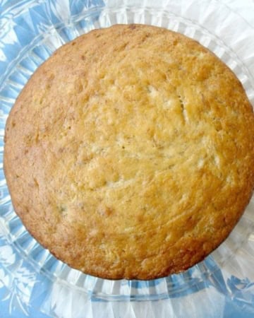 Overhead vintage banana cake on a vintage cake plate and tablescloth.