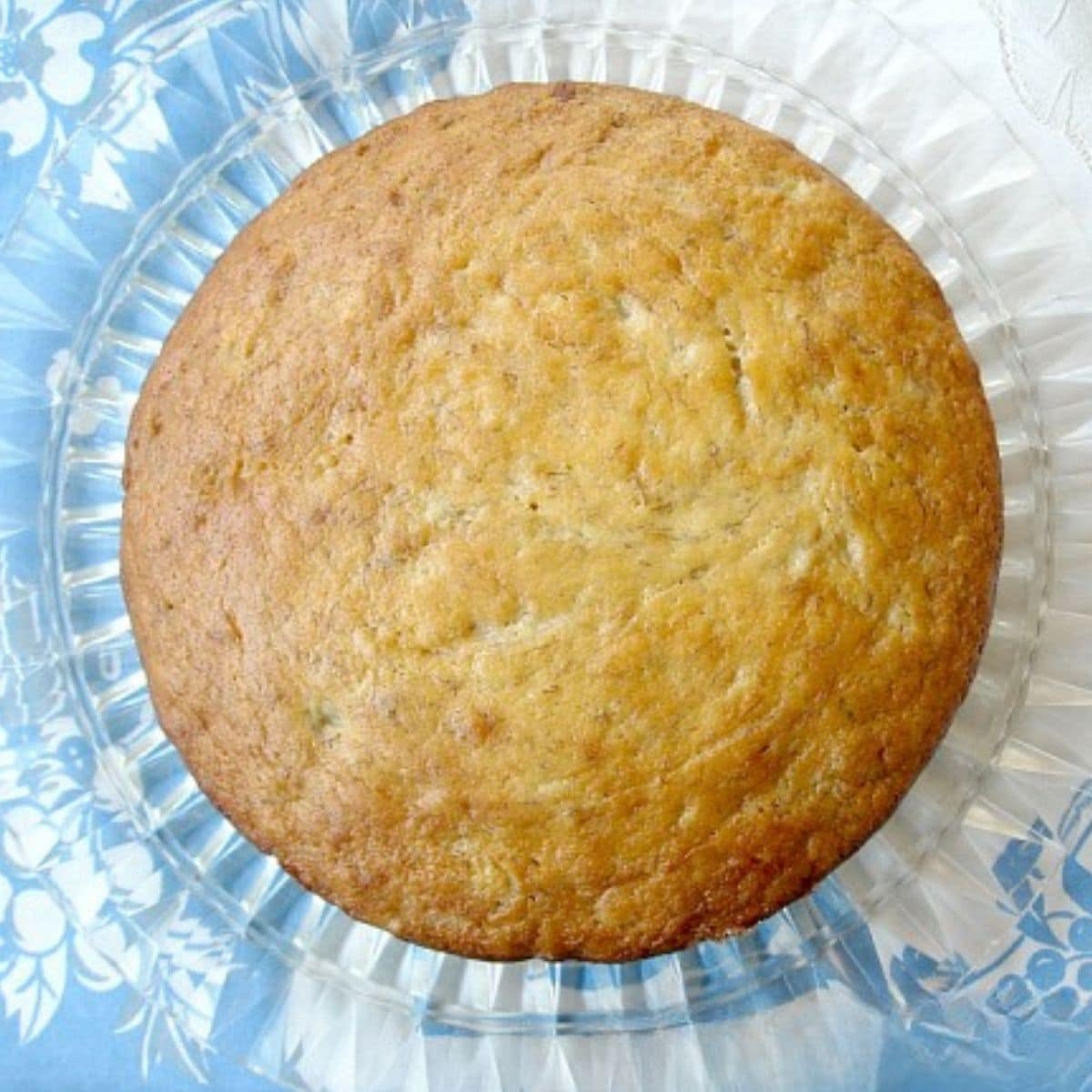 Overhead vintage banana cake on a vintage cake plate and tablescloth.