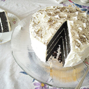 Vegan Triple Layer Chocolate Cake recipe on a vintage glass cake plate with a slice cut and on a cake plate.