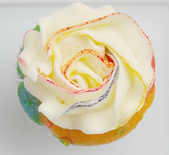 A rainbow cupcake with rosette frosting