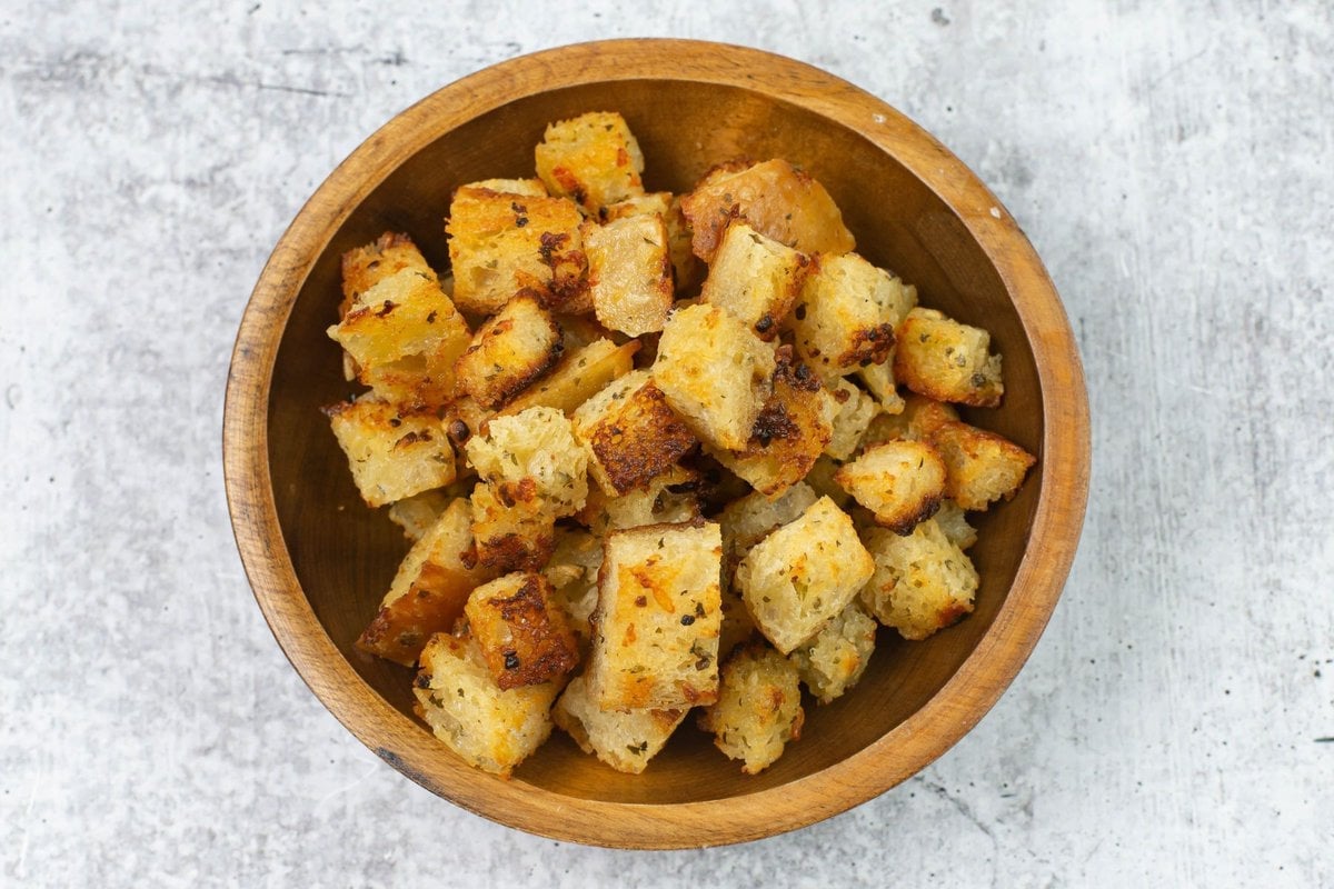 Parmesan seasoned croutons in a small wooden bowl.