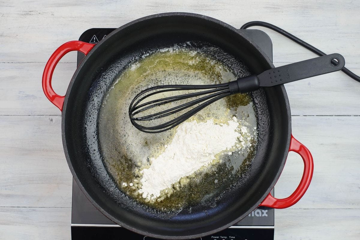Adding flour to melted butter in a skillet.