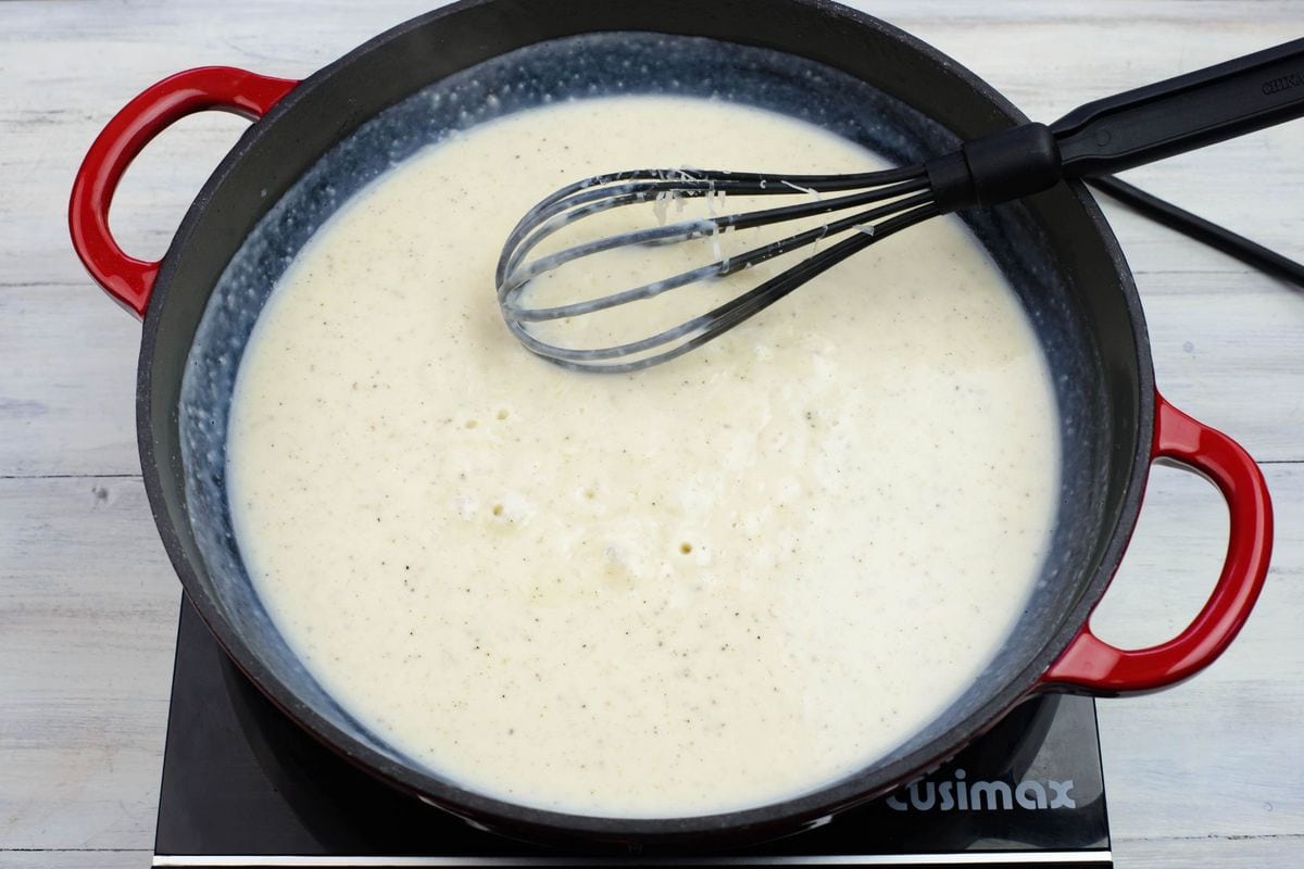 Bubbling alfredo sauce in a skillet.