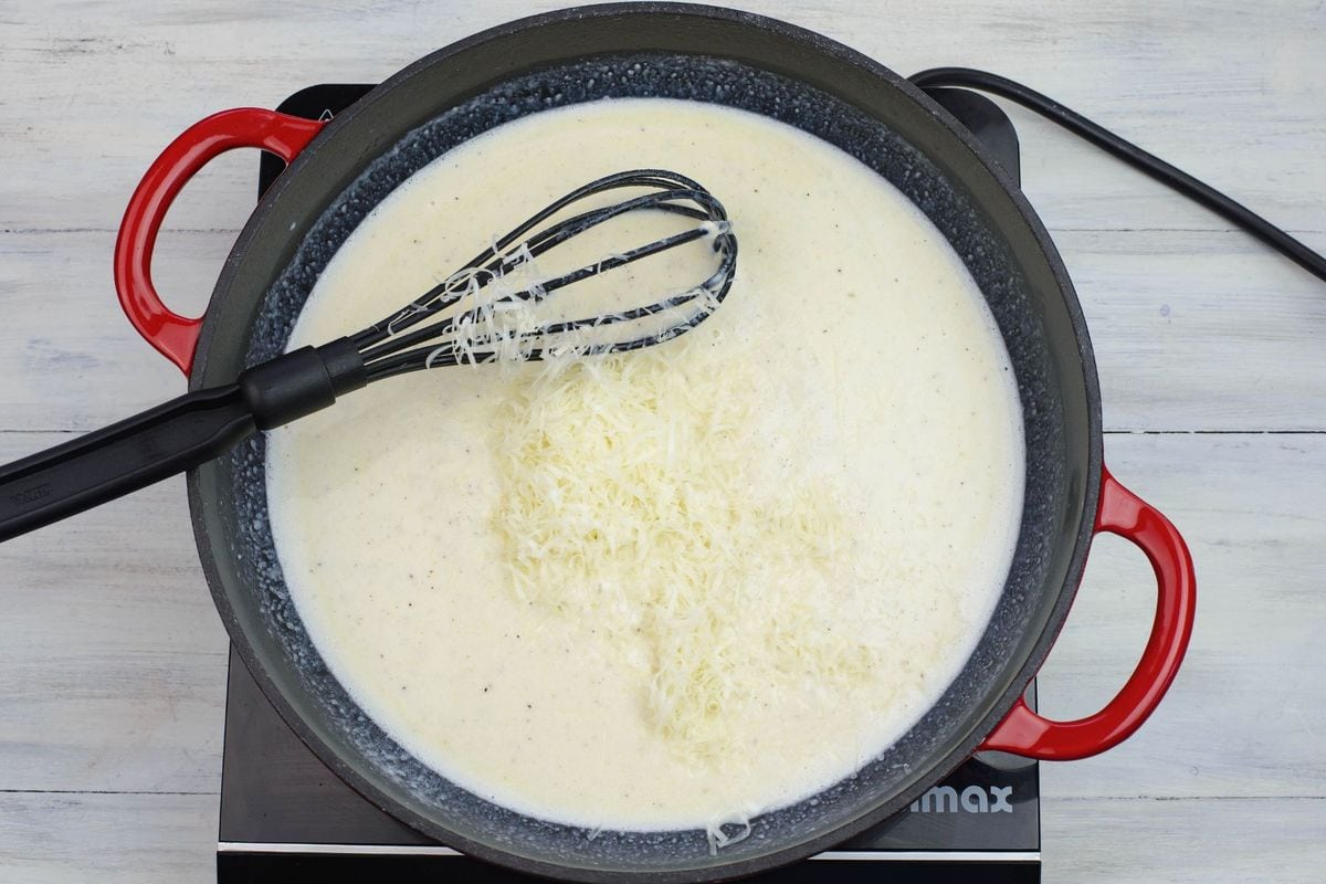 Adding shredded Parmesan cheese to the pan.