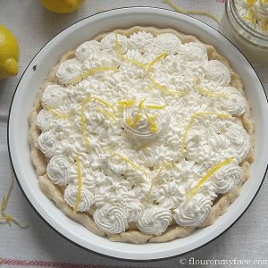overhead photo of a pie topped with whipped cream swirls and lemon zest