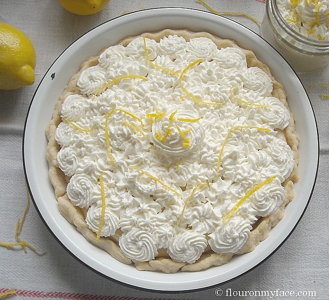 overhead photo of a pie topped with whipped cream swirls and lemon zest