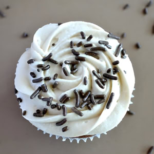 Overhead view of brownie cupcake frosting topped with sprinkles.