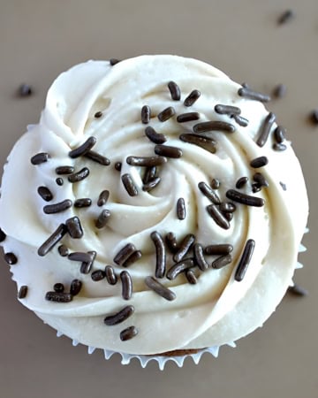 Overhead view of brownie cupcake frosting topped with sprinkles.