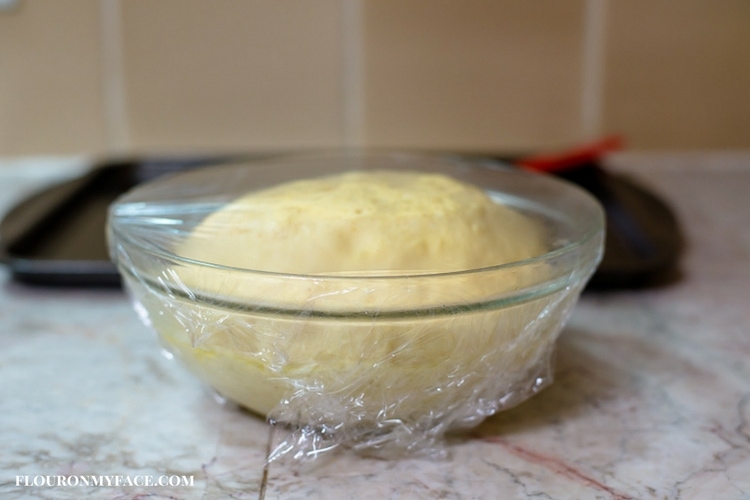Slider bun dough rising in a clear glass bowl so you can see when the dough has doubled in size.