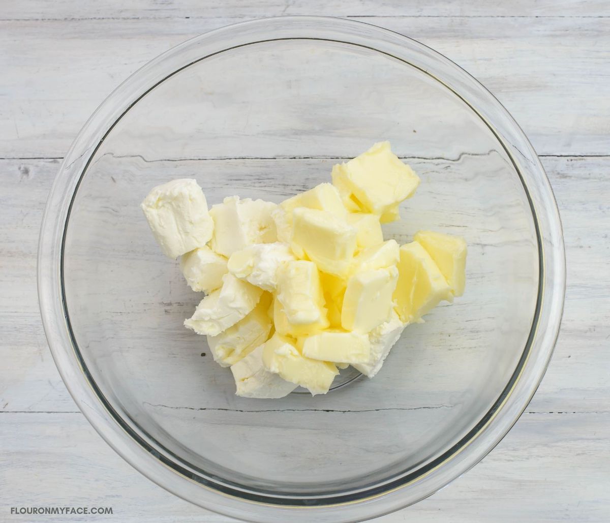 Softened butter and cream cheese cut into cubes in a bowl.