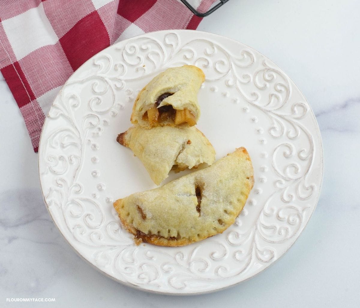 Two apple turnovers on a dessert plate.