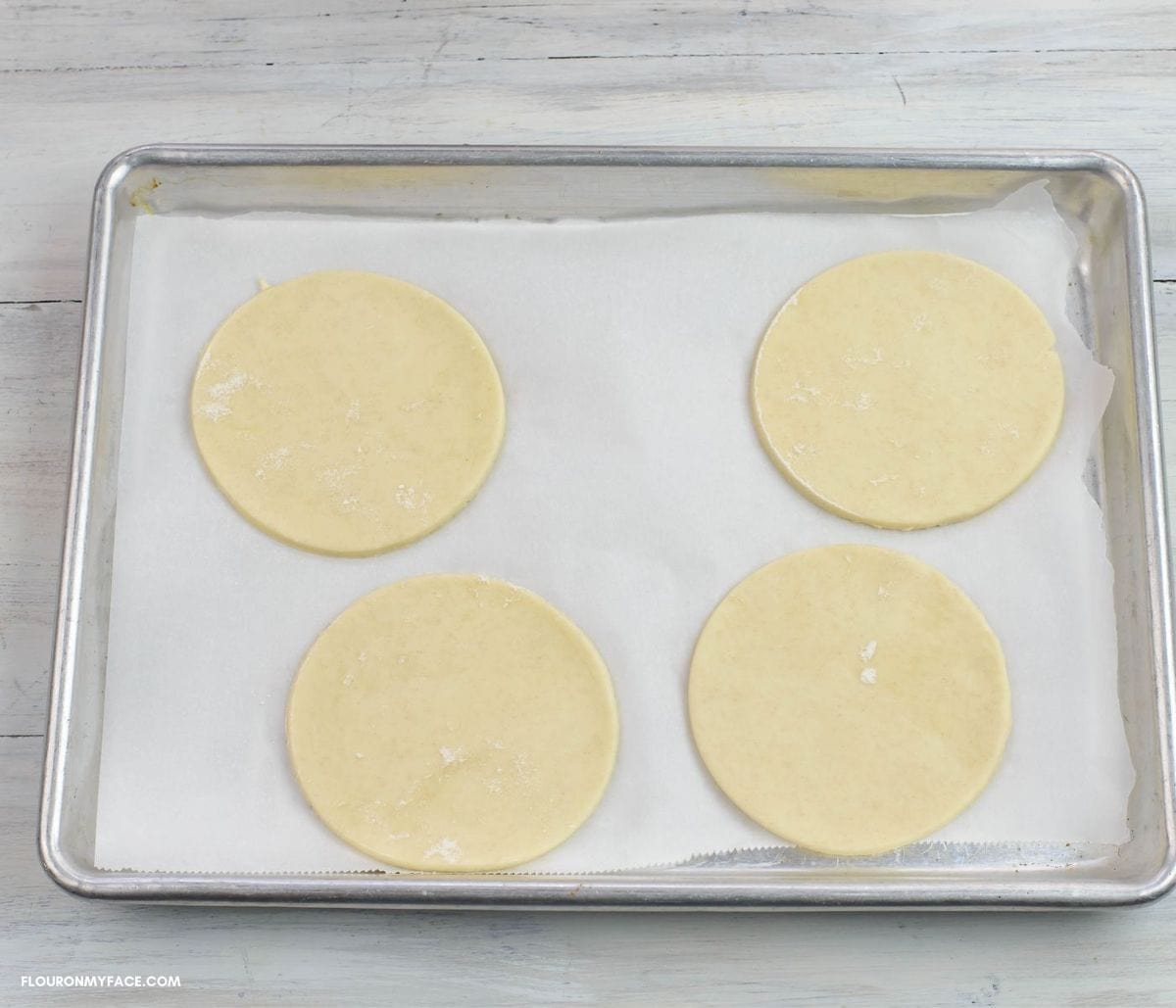 Turnover dough circles on a baking sheet.