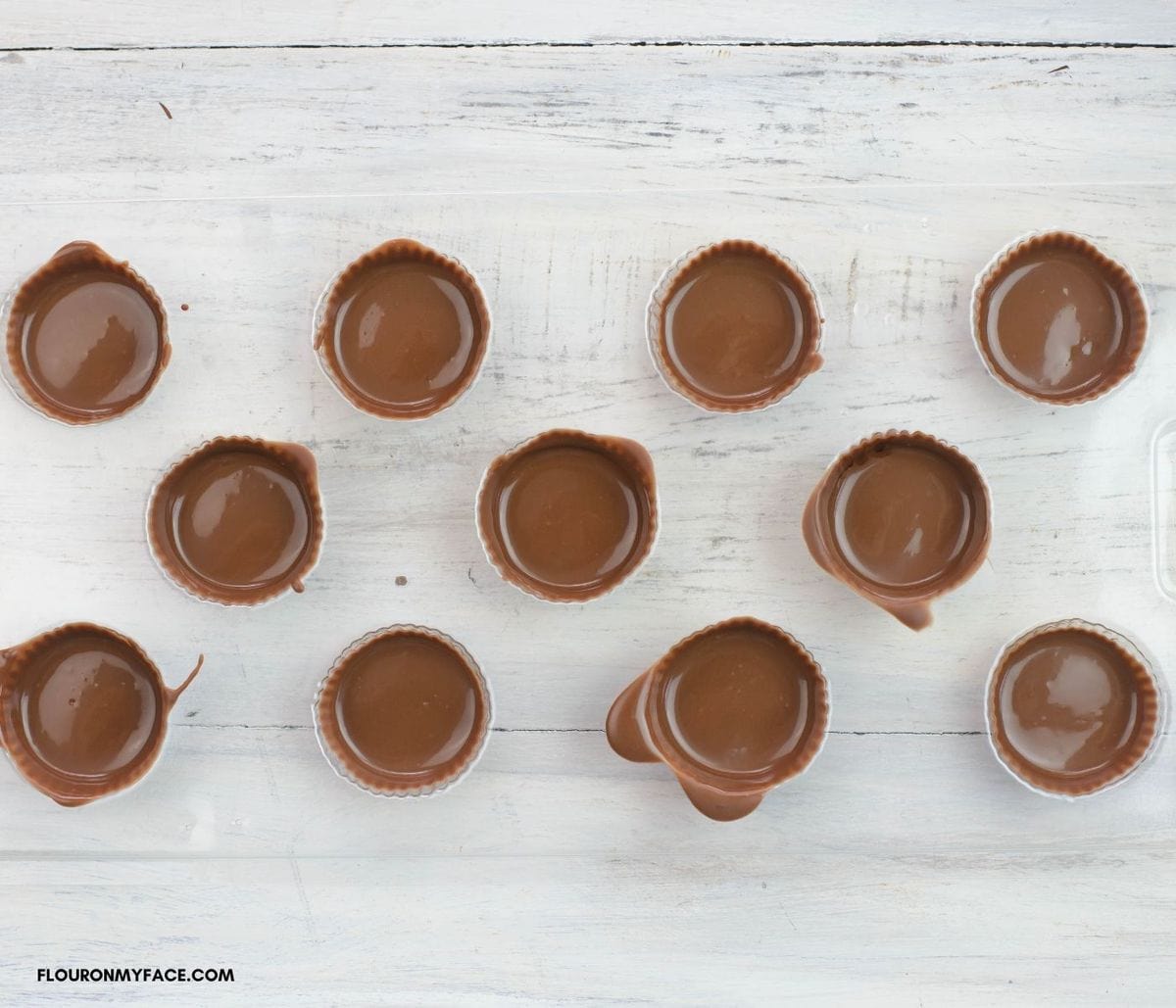 Overhead image of a mini cups candy mold coated with melted chocolate.