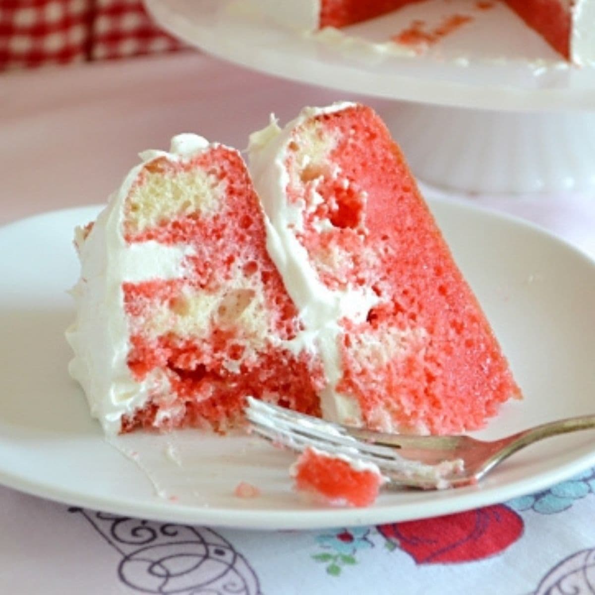 A slice of Strawberry poke cake on a dessert plate.