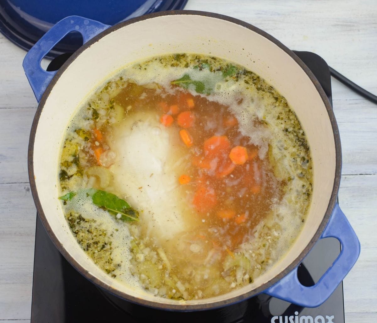 Chicken soup boiling in a Dutch oven.