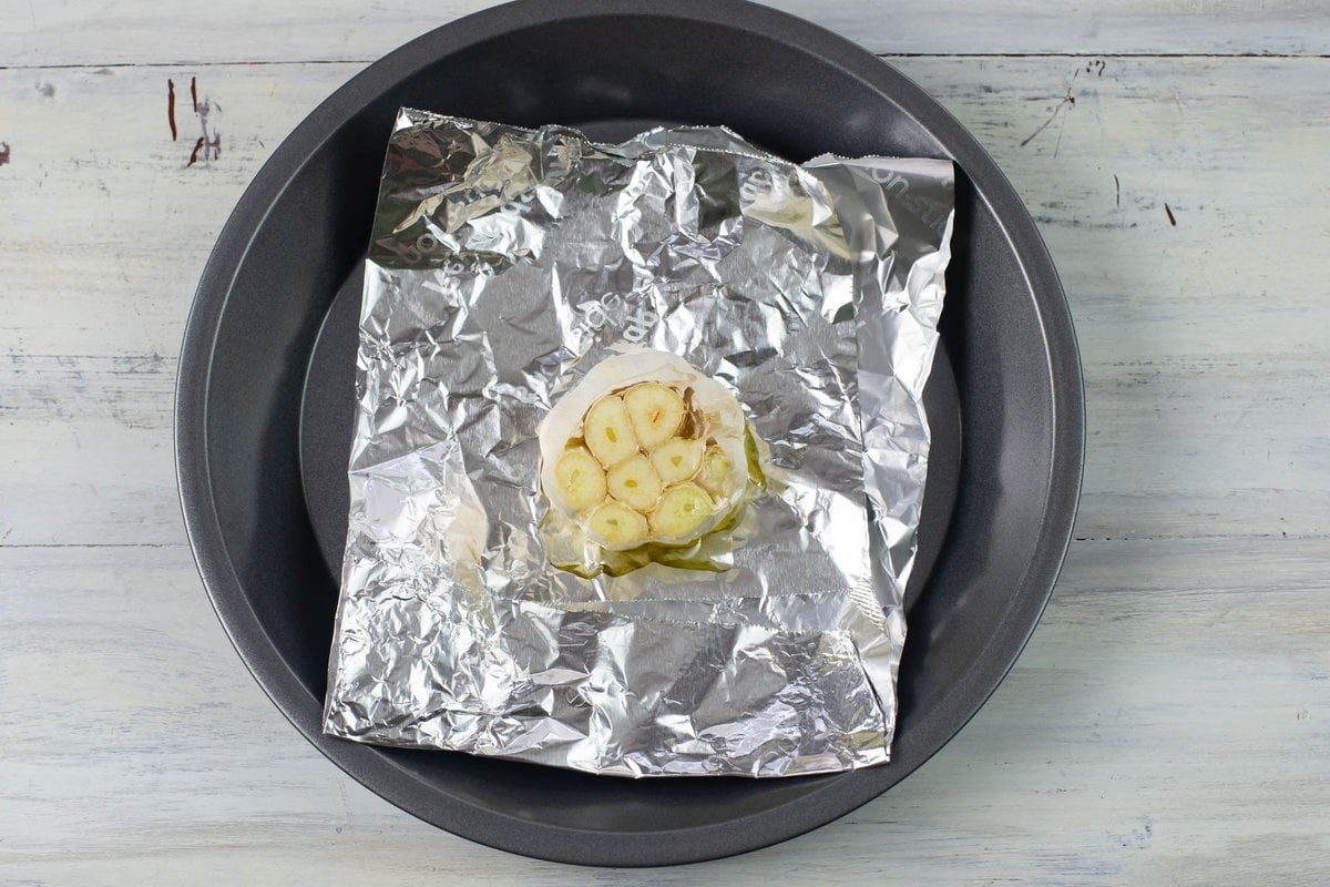 One garlic head placed down into the center of aluminum foil before roasting.