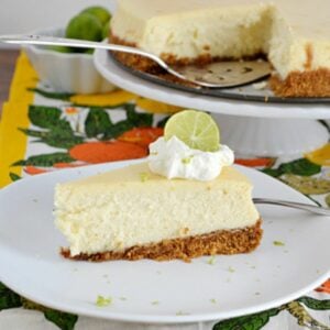 Slice of Key Lime Cheesecake garnished with whipped cream and lime wedge.
