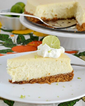 Slice of Key Lime Cheesecake garnished with whipped cream and lime wedge.