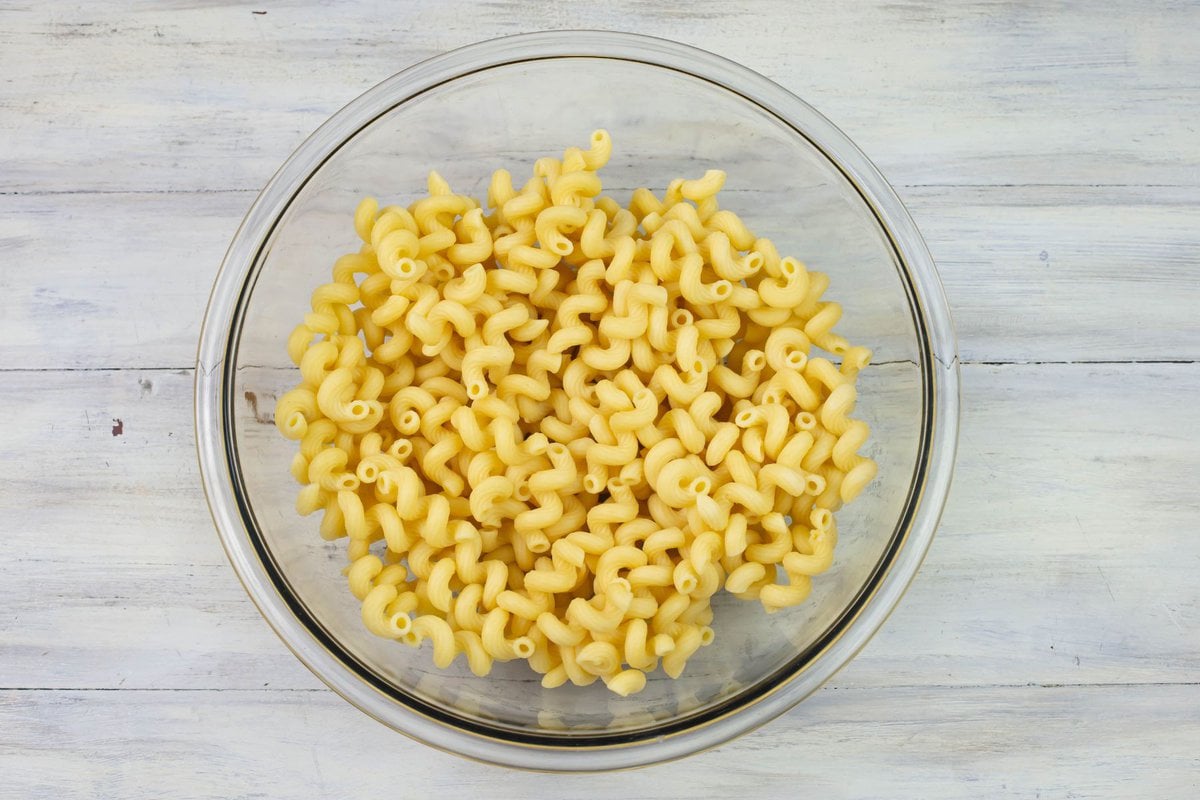 Cooked Cellentani pasta noodles in a large glass mixing bowl.