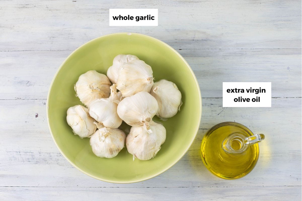 Whole garlic heads and a bottle of olive oil on a tabletop.