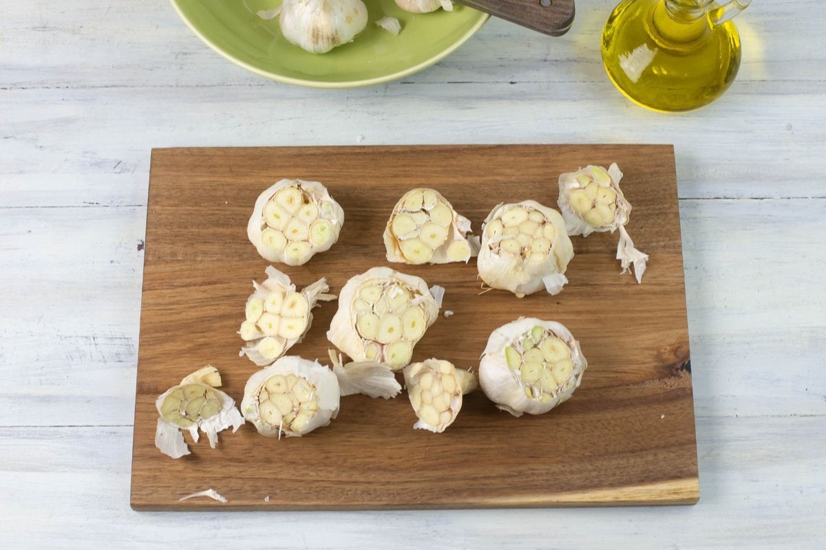 Cutting the tops off whole garlic heads to roast.