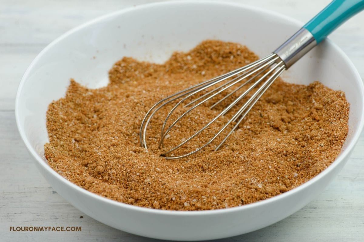 Mixing rub spices together in a bowl with a whisk.