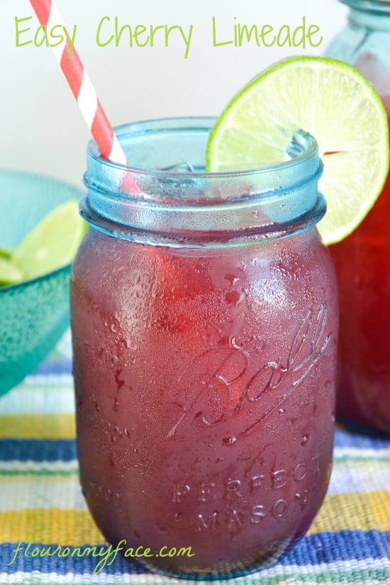 a blue heritage mason jar filled with my easy Cherry Limeade recipe, with a paper straw and a slice of lime on the lip of the glass.
