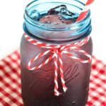 Blue vintage mason jar filled with homemade black cherry soda