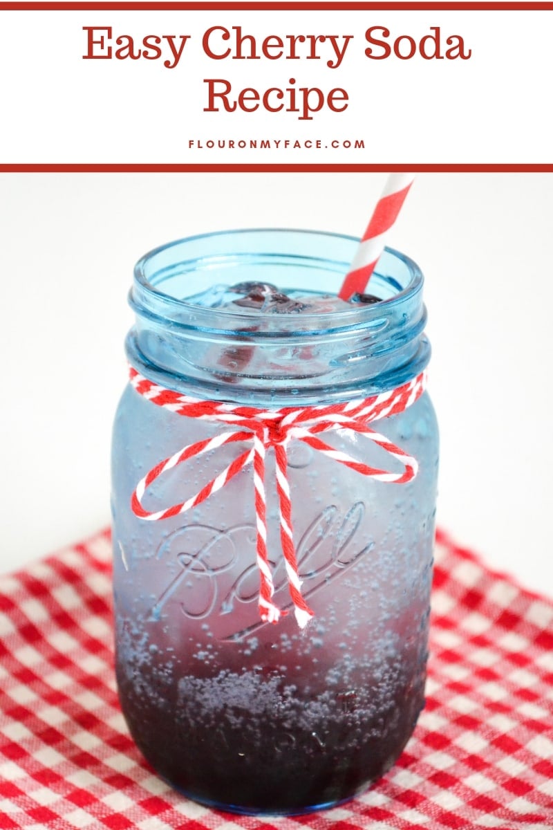 blue mason jar filled with a layered drink recipe for easy cherry soda.