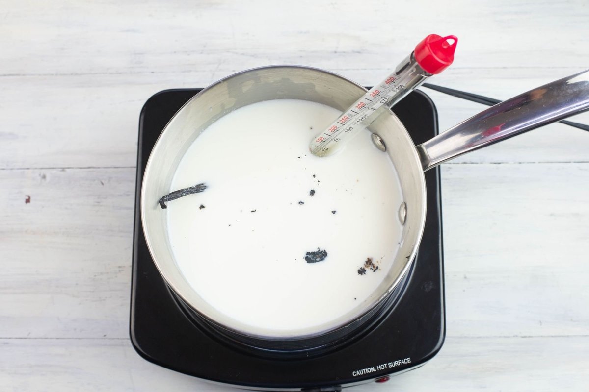 Milk, vanilla bean pod and seeds in a aluminum pot.