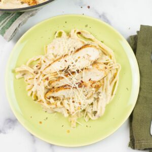 A serving of Spicy Cajun Chicken Fettuccine Alfredo on a green dinner plate.