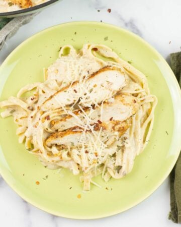A serving of Spicy Cajun Chicken Fettuccine Alfredo on a green dinner plate.