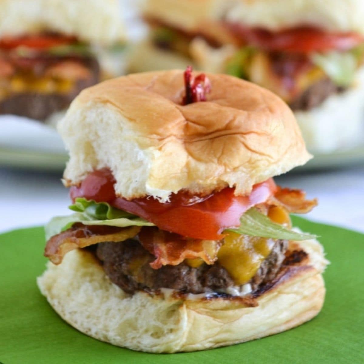 Closeup of a stuffed cheeseburger slider with bacon, tomato and lettuce.