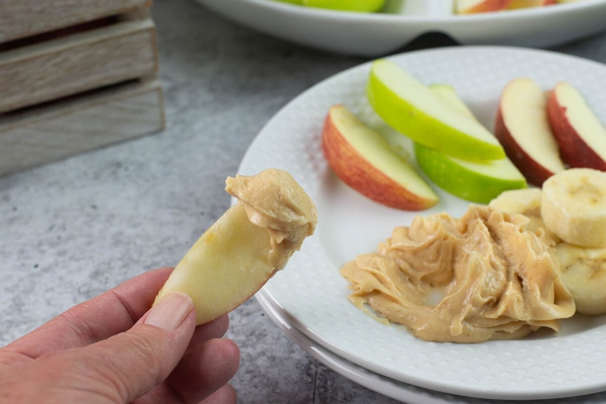 Apple slice held in my hand after being dipped into peanut butter dip.