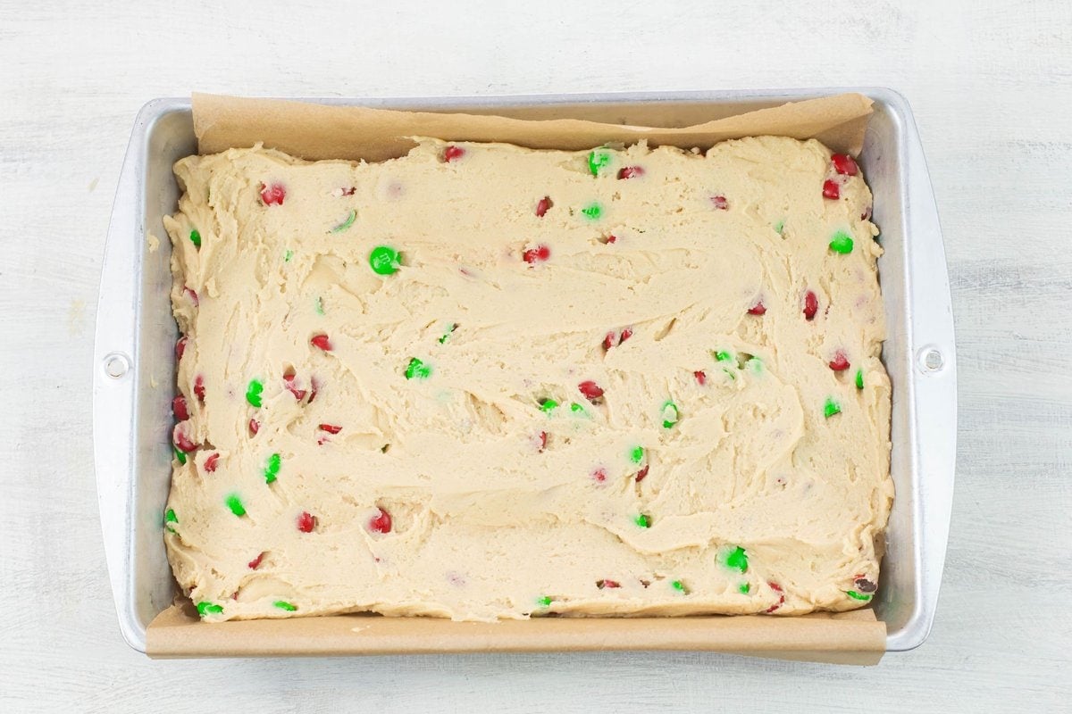 Unbaked M&M Sugar Cookie bars spread into a baking tray.