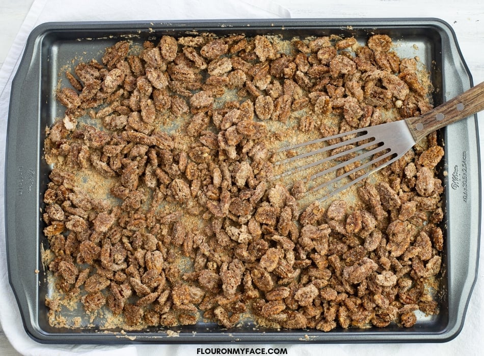 a baking sheet covered with freshly baked candied pecans.