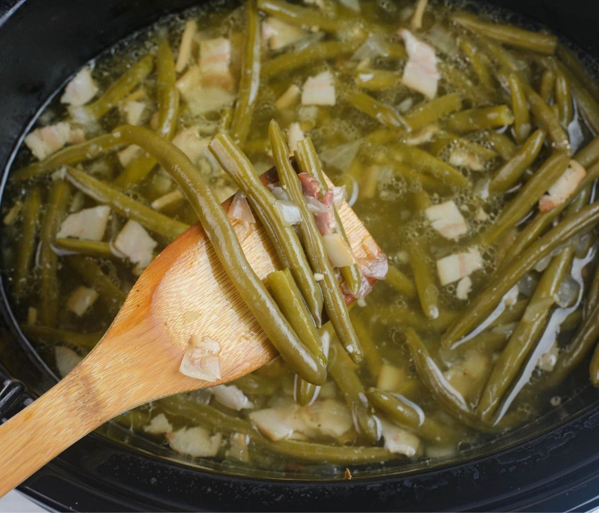 A wooden spoon with a serving of green beans.