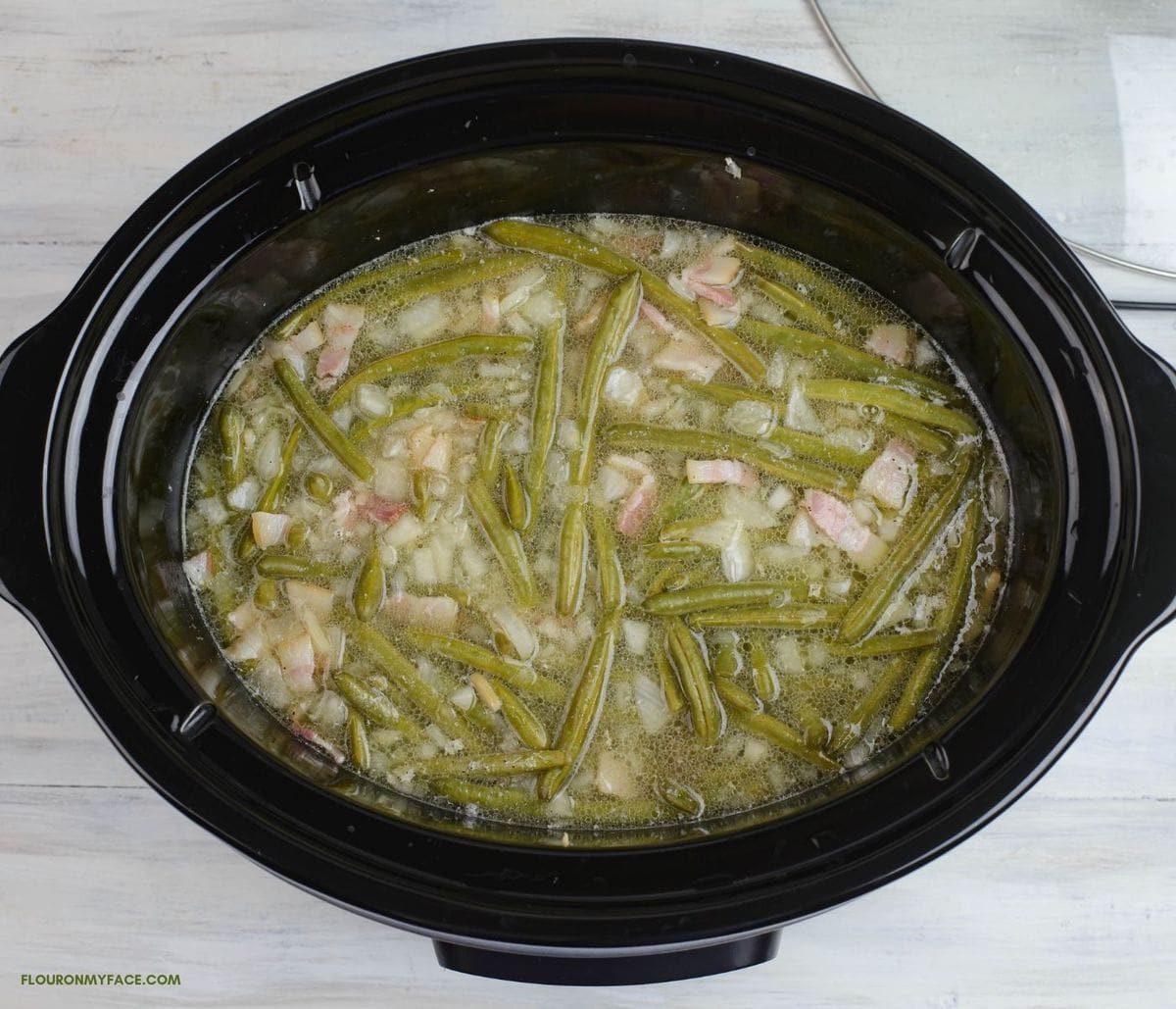 Fresh green beans covered with chicken broth before slow cooking.