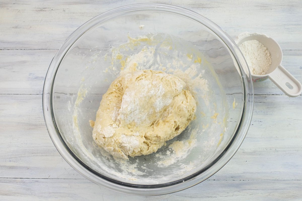 Parcially kneaded dough in a bowl with a dusting of flour on the surface.