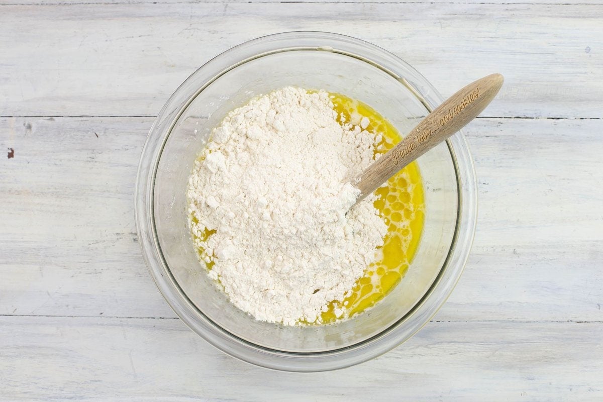 Adding flour to the bowl of sourdough sponge ingredients.