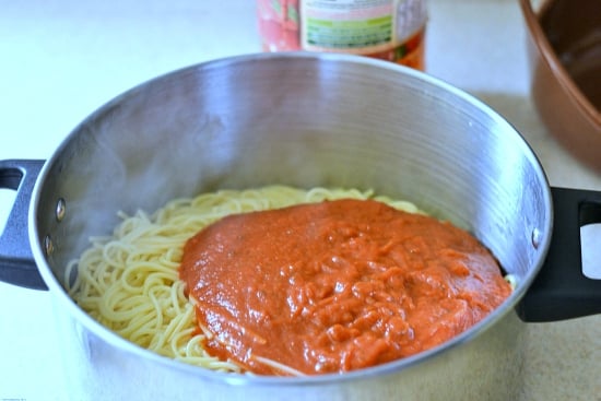 A large pot filled with cooked spaghetti noodles with sauce poured over them.