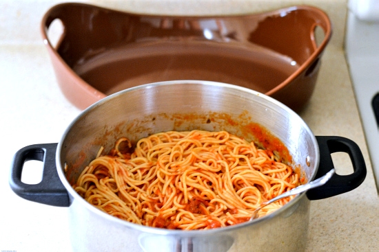 Spaghetti noodles combined with pasta sauce in a large pot.