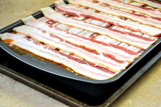 homemade baked beans ingredients in a 9 x 13 inch baking pan covered with sliced bacon