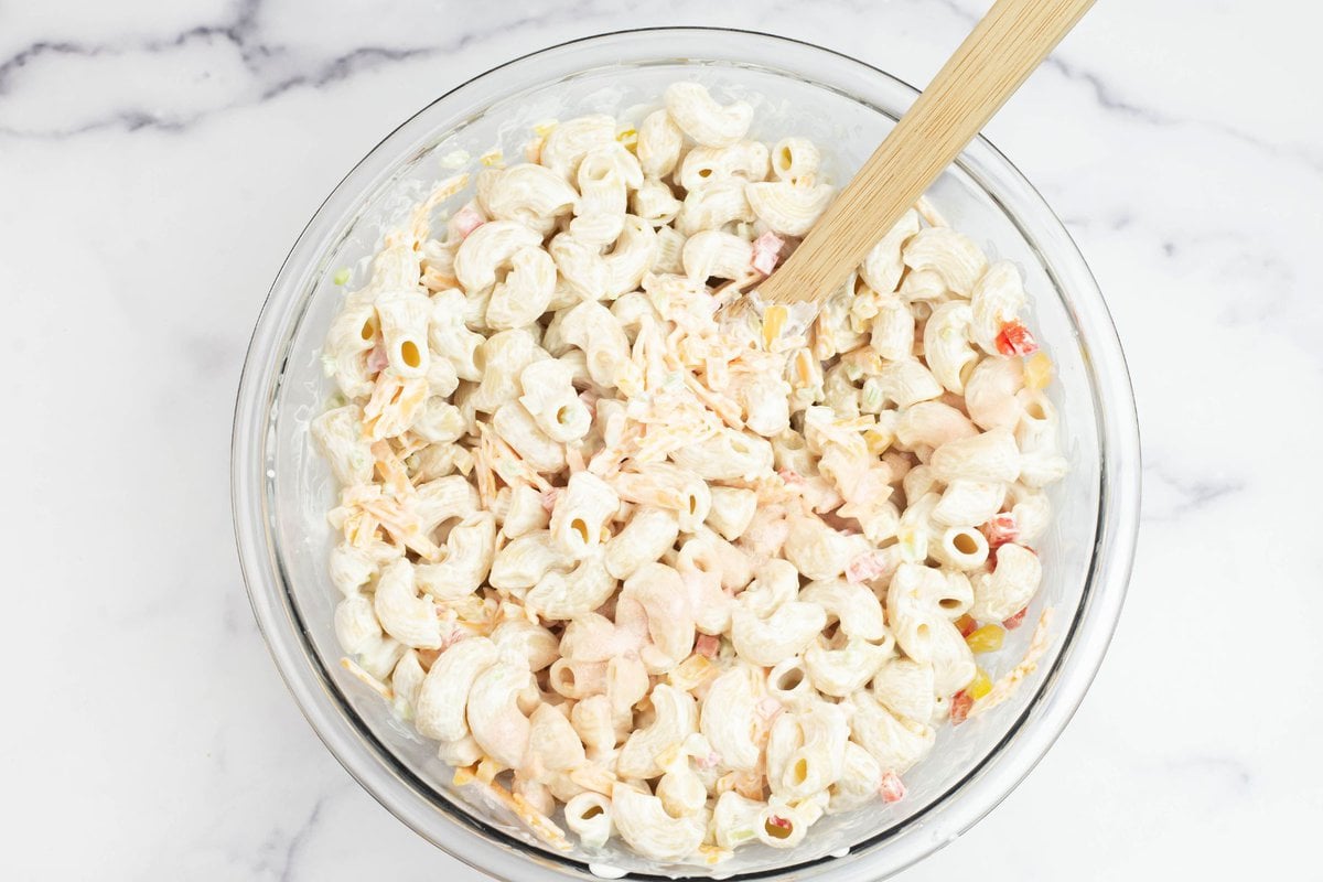 Cheddar pasta salad mixed together in a glass bowl.